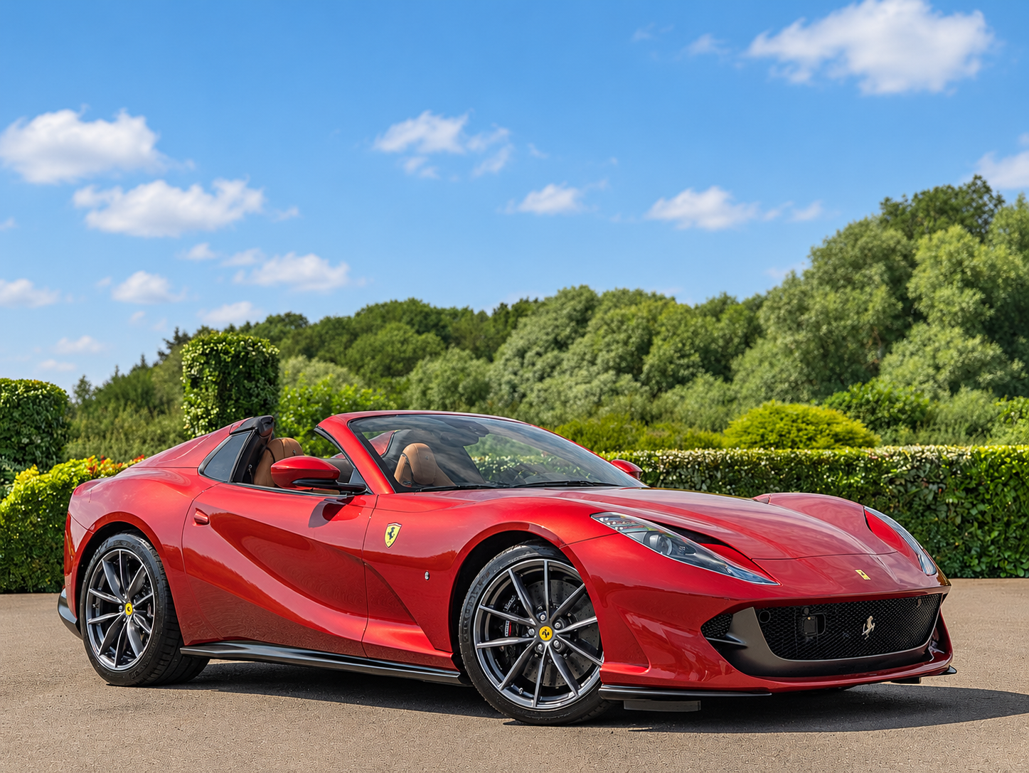 Red Ferrari convertible facing right beneath a blue sky
